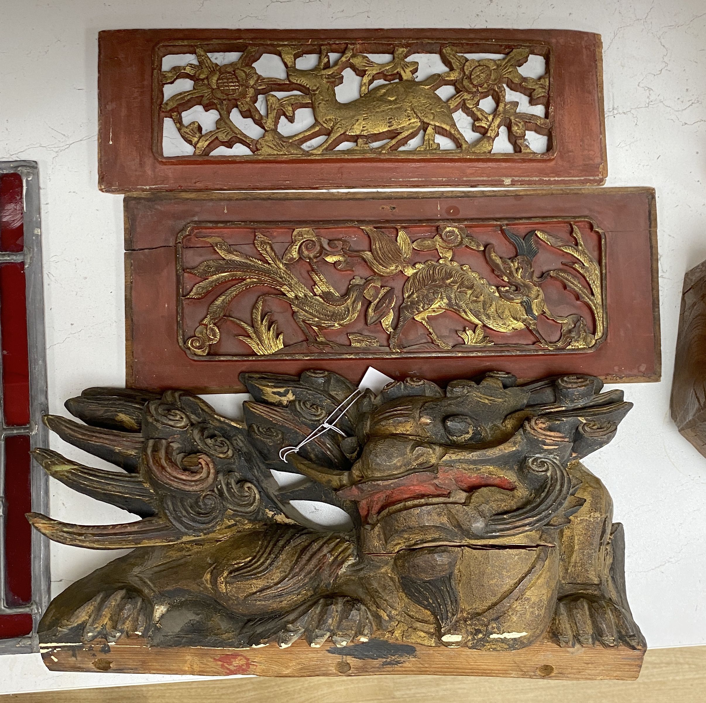An early 20th century Chinese carved and polychrome painted wooden temple dragon, 21 x 38cm, together with a pair of carved and gilded